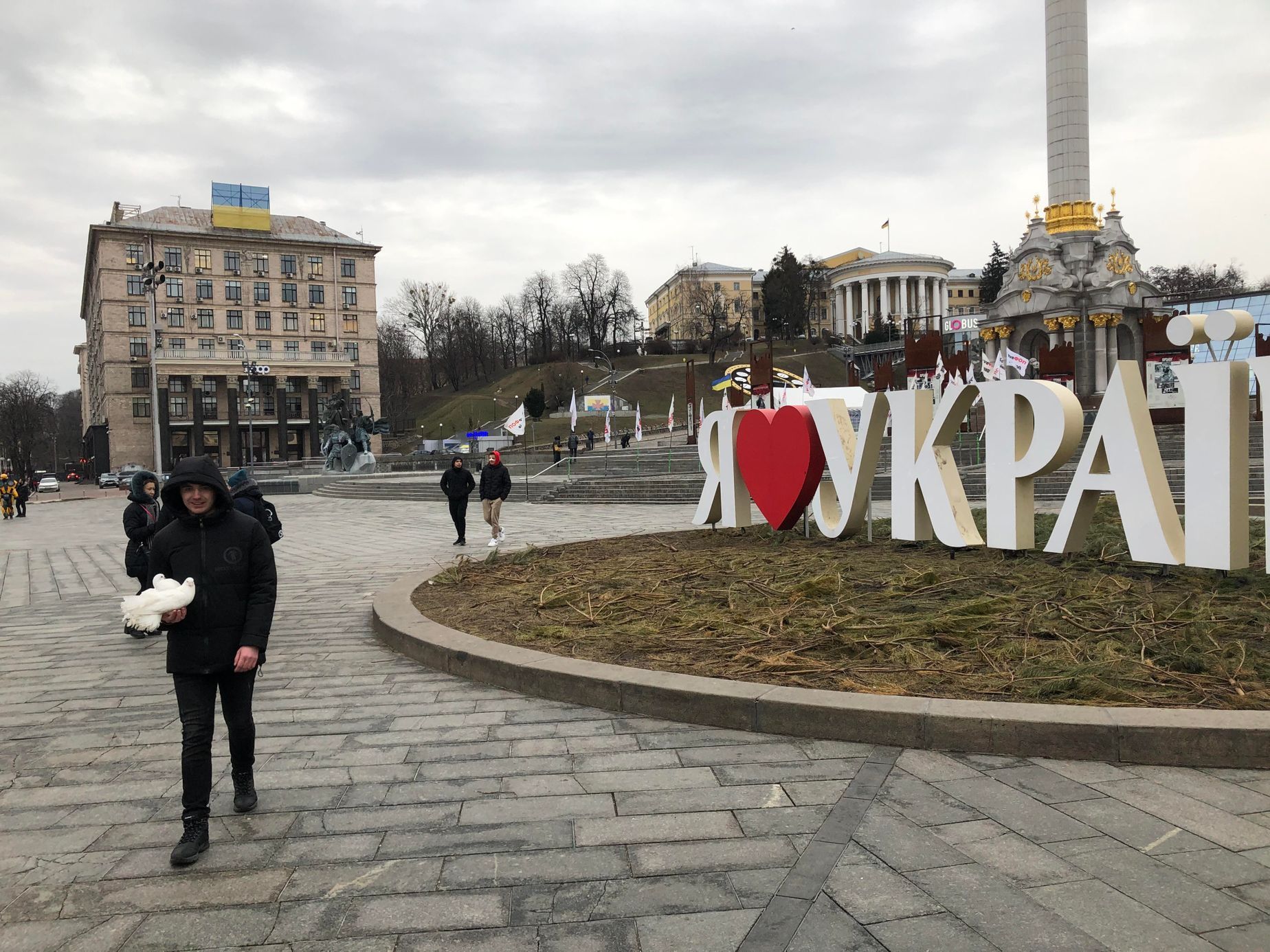 Muž kráčí v centru Kyjeva se dvěma bílými holubicemi. Ale na mír to zatím nevypadá.