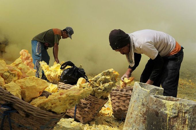 This photo taken on December 25, 2010 shows an Indonesian miner filling baskets with sulphur before carrying them from the bottom of the crater of Indonesia's active Kajah Iwen volcano, in the extreme east of Java island. Some 350 sulphur miners eke out a dangerous and exhausting living on the active volcano, carrying hauls of up to 80 kilos of "yellow gold" which will be bought by local factories and used to refine sugar or make matches and medicines. The miners extract the liquid sulphur as it flows out of hot iron pipes. Once in the open air, it cools, crystallises and turns bright yellow. The sulphur is then loaded into wicker baskets at either end of bamboo yokes and carried back over the lip of the crater and down the side of the volcano, a treacherous journey of four kilometres (2.5 miles).