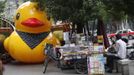 A scaled replica of the "Rubber Duck" by Dutch conceptual artist Florentijn Hofman is seen along a street next to a vendor waiting for customers in Shanghai, June 13, 2013. REUTERS/Aly Song (CHINA - Tags: SOCIETY TPX IMAGES OF THE DAY) Published: Čer. 13, 2013, 1:30 odp.