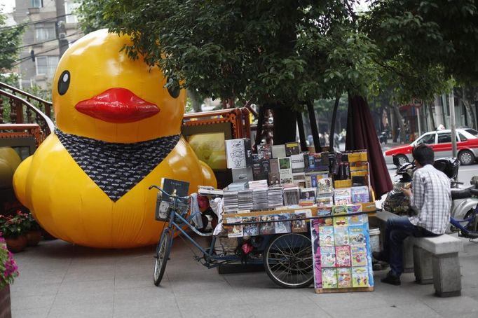 A scaled replica of the "Rubber Duck" by Dutch conceptual artist Florentijn Hofman is seen along a street next to a vendor waiting for customers in Shanghai, June 13, 2013. REUTERS/Aly Song (CHINA - Tags: SOCIETY TPX IMAGES OF THE DAY) Published: Čer. 13, 2013, 1:30 odp.