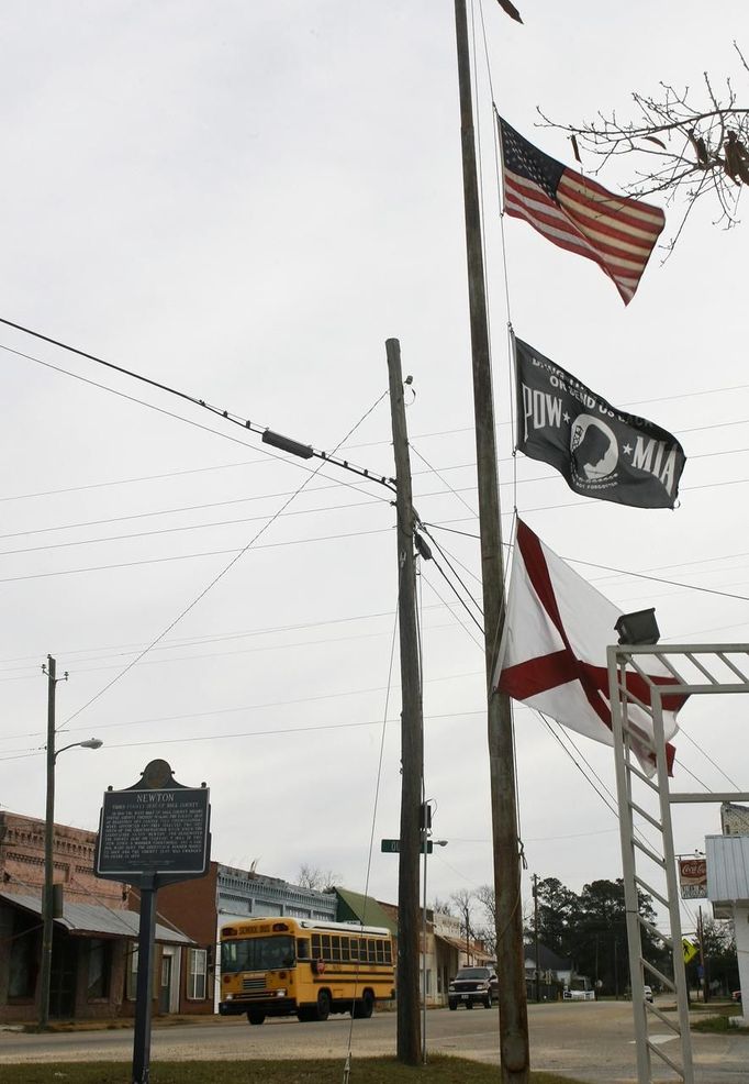 A Dale County Alabama school bus passes flags flying at half staff in Newton, Alabama, near Midland City, Alabama February 1, 2013. Residents in a rural Alabama town prayed on Friday and called for the release of a 5-year-old boy being held captive for a fourth day by a man accused of shooting a school bus driver and then taking the child hostage. REUTERS/Phil Sears (UNITED STATES - Tags: CRIME LAW) Published: Úno. 1, 2013, 9:32 odp.