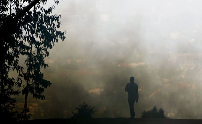 Muž stojí na kopci nad Addis Abebou v Etiopii. I tady místní obyvatele sužuje silný smog.