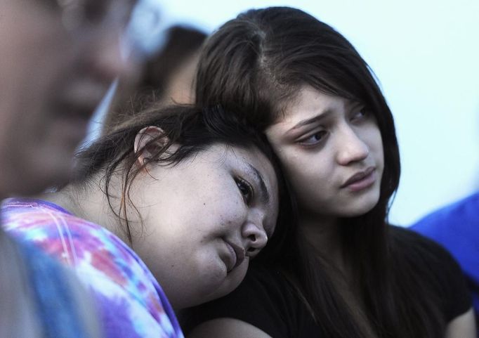 Mary Hamilton (L) puts her head on the shoulder of her friend Stephanie Rodriquez during a vigil for victims behind a theater where a gunman open fire on moviegoers in Aurora, Colorado July 20, 2012. A total of 71 people were shot in Friday's rampage at the Denver-area movie theater that has left 12 people dead, the local police chief said. The suspect, identified by police as James Eagan Holmes, 24, also booby-trapped his Aurora apartment with sophisticated explosives, creating a hazard for law-enforcement and bomb squad officers who swarmed to the scene. REUTERS/ Jeremy Papasso (UNITED STATES - Tags: CRIME LAW TPX IMAGES OF THE DAY) Published: Čec. 21, 2012, 3:48 dop.