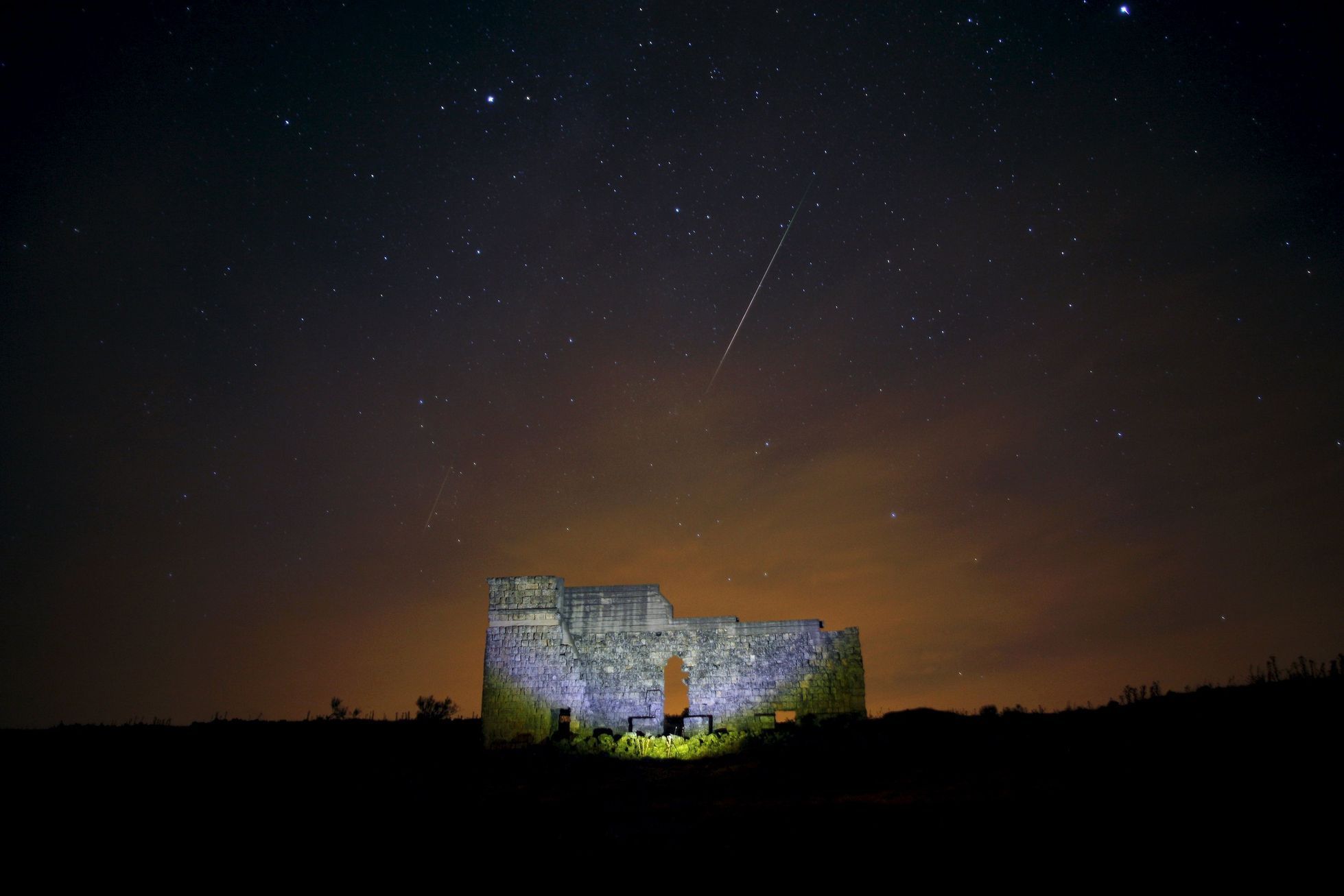 Meteors streak across the sky over a Roman theatre in the ruins of Acinipio, during the Perseid meteor shower near Ronda