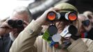 Race-goers watch the race through binoculars during the Cheltenham Festival horse racing meet in Gloucestershire, western England March 13, 2012.