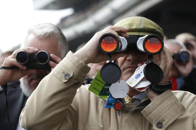 Race-goers watch the race through binoculars during the Cheltenham Festival horse racing meet in Gloucestershire, western England March 13, 2012.