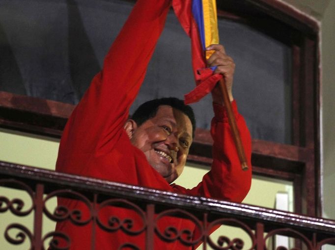 Venezuelan President Hugo Chavez holds the national flag while celebrating from a balcony at the Miraflores Palace in Caracas October 7, 2012. Venezuela's socialist President Chavez won re-election in Sunday's vote with 54 percent of the ballot to beat opposition challenger Henrique Capriles. REUTERS/Tomas Bravo (VENEZUELA - Tags: POLITICS ELECTIONS) Published: Říj. 8, 2012, 6:22 dop.