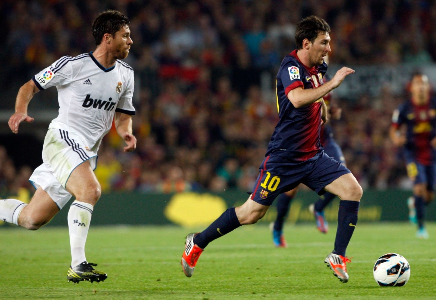 Fotbalista Realu Madrid Xabi Alonso stíhá Lionela Messiho v utkání Primera División 2012/13 proti Barceloně.