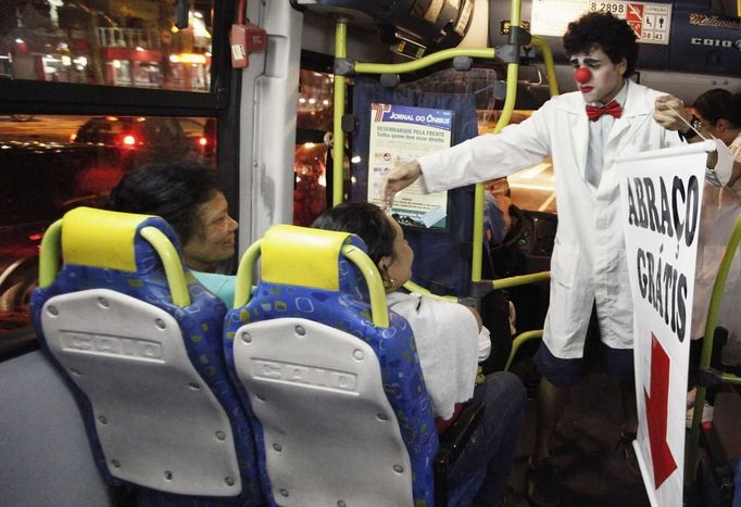 A member of the Traffic Psychologists holds a banner as he performs inside a bus in Sao Paulo July 23, 2012. Traffic Psychologists is a non-profit non-governmental organization which aims to humanize traffic and reduce the level of stress caused to drivers. Sao Paulo has more than 7 million vehicles, according to figures from the state transport authority Detran. Banner reads "Free Hugs". Picture taken July 23, 2012. REUTERS/Nacho Doce (BRAZIL - Tags: TRANSPORT SOCIETY) Published: Čec. 24, 2012, 6:59 dop.