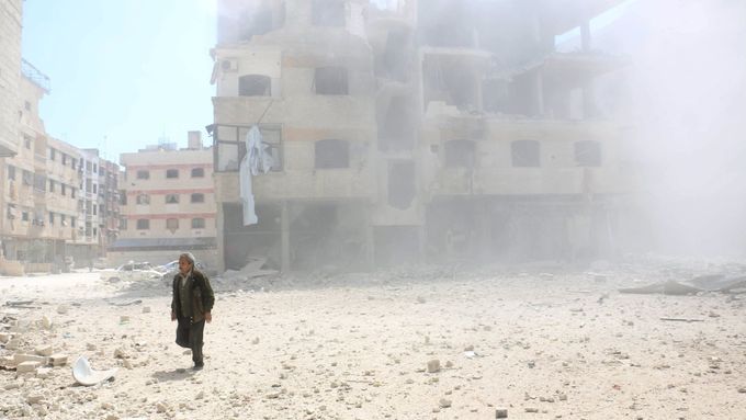 Muž jde kolem bombardované budovy na damašském předměstí Ghúta.