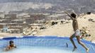 A boy jumps into a portable swimming pool at Manshiyet Nasser shanty town in eastern Cairo June 28, 2012. The pool offers respite from the summer heat and is installed for children whose parents can't afford travelling to the northern Egypt beaches. For 1 Egypt pound ($0.16) children are allowed to play in the water for three hours. The area were the swimming pool is installed is named "Porto Dweiqat Um Ahmed". REUTERS/Amr Abdallah Dalsh (EGYPT - Tags: ENVIRONMENT SOCIETY POVERTY) Published: Čer. 28, 2012, 4:13 odp.