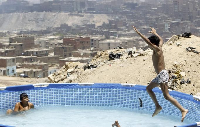 A boy jumps into a portable swimming pool at Manshiyet Nasser shanty town in eastern Cairo June 28, 2012. The pool offers respite from the summer heat and is installed for children whose parents can't afford travelling to the northern Egypt beaches. For 1 Egypt pound ($0.16) children are allowed to play in the water for three hours. The area were the swimming pool is installed is named "Porto Dweiqat Um Ahmed". REUTERS/Amr Abdallah Dalsh (EGYPT - Tags: ENVIRONMENT SOCIETY POVERTY) Published: Čer. 28, 2012, 4:13 odp.