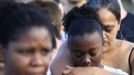 People grieve during a vigil for victims behind the theater where a gunman opened fire on moviegoers in Aurora, Colorado July 20, 2012. A total of 71 people were shot in Friday's rampage at the Denver-area movie theater that has left 12 people dead, the local police chief said. The suspect, identified by police as James Eagan Holmes, 24, also booby-trapped his Aurora apartment with sophisticated explosives, creating a hazard for law-enforcement and bomb squad officers who swarmed to the scene. REUTERS/Shannon Stapleton (UNITED STATES - Tags: CRIME LAW) Published: Čec. 21, 2012, 1:39 dop.