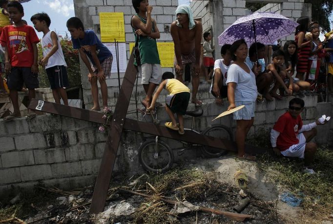 Residents stand in front of a wooden cross on which penitent had been hung during a Good Friday crucifixion re-enactment in San Juan village, Pampanga province, north of Manila March 29, 2013. About two dozen Filipinos were nailed to crosses on Good Friday in an extreme display of devotion that the Catholic church looks down upon as a form of folk religion but appears powerless to stop. Holy Week is celebrated in many Christian traditions during the week before Easter. REUTERS/Romeo Ranoco (PHILIPPINES - Tags: RELIGION SOCIETY) Published: Bře. 29, 2013, 10:32 dop.