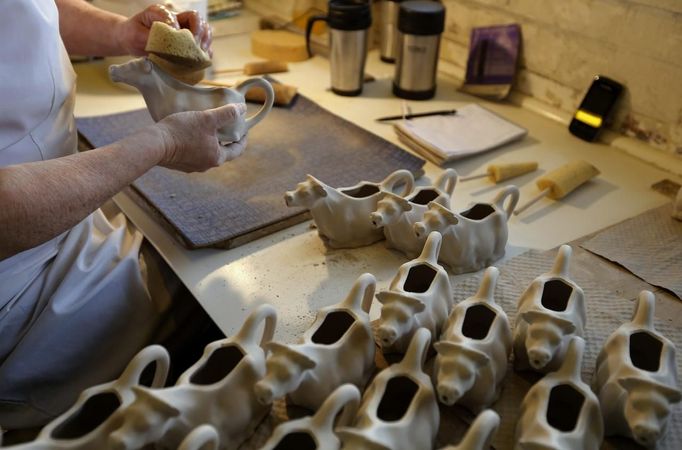 A worker uses a sponge to wipe down a cow shaped creamer jug at the Middleport pottery in Stoke-on-Trent, central England January 22, 2013. The pottery which dates back to 1888 and was rescued from closure in 2009, continues to use traditional methods to produce its range of ceramics and famous Burleigh Ware pottery. REUTERS/Phil Noble (BRITAIN - Tags: BUSINESS EMPLOYMENT SOCIETY) Published: Led. 22, 2013, 4:23 odp.