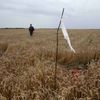 A member of the Ukrainian Emergency Ministry walks past a white flag marking the location of a body, close to the site of Thursday's Malaysia Airlines Boeing 777 plane crash near Grabovo