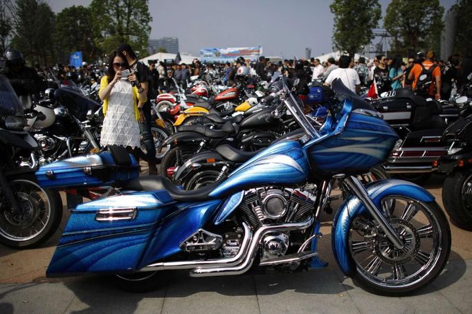 A woman takes a picture of a Harley Davidson motorcycle during the annual Harley Davidson National Rally in Qian Dao Lake, in Zhejiang Province May 11, 2013. Around 1,000 Harley Davidson enthusiasts from all over China met to celebrate the 5th Harley Davidson National Rally in China, as part of the company's 110-year anniversary. Major Chinese cities ban motorcycles from circulating on highways and major avenues. Meanwhile, Harley Davidson motorbikes are considered by Chinese tax authorities to be luxury items, so they are taxed at extremely high rates-- sometimes the taxes alone is equivalent to the bike's U.S. price tag. Traffic and transportation authorities have also weighed in, putting Harleys in the same category as electric bikes, horses and bicycles, meaning that they cannot be on highways and major avenues. Picture taken May 11, 2013. REUTERS/Carlos Barria (CHINA - Tags: TRANSPORT SOCIETY) Published: Kvě. 13, 2013, 11:05 odp.