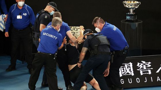 Ochranka spolu s policisty odtahuje výtržníka, který vběhl na kurt během finále Australian Open 2022