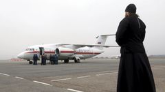An Orthodox priest looks at a Russian emergencies ministry's plane, carrying the remains of victims of the plane crash in Egypt, shortly after its landing on the airfield of Pulkovo airport outside St