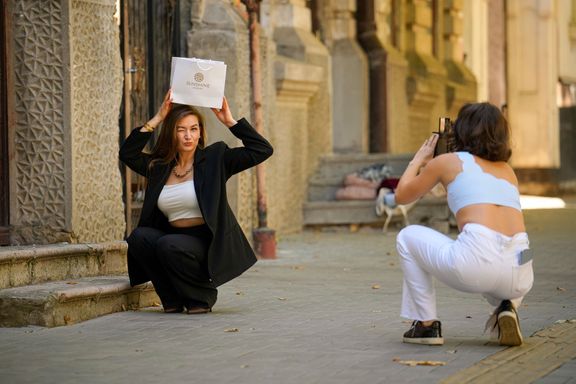 Z cyklu Běžný život v Moldavsku před volbami. Juliana (nalevo) pózuje Anastasiji, zatímco fotí fotografie k propagaci šperků. 23. září 2025, Kišiněv.