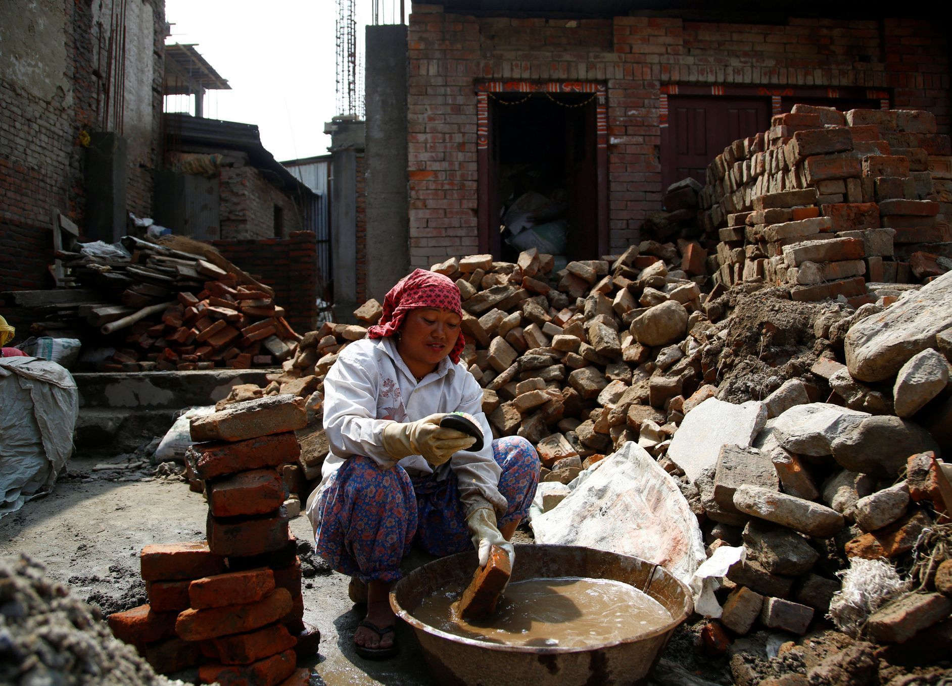 Žena v Bhaktapuru sbírá cihly ze zřícenin domu, kde dříve bydlela.