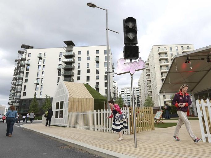 Guests and staff walk outside the Globe bar in the Olympic Village built for the London 2012 Olympic Games in Stratford, east London on June 29, 2012. The Globe will be a dry bar for the duration of the games. The village will accomodate up to 16,000 athletes and officials from more than 200 nations. Picture taken June 29, 2012. REUTERS/Olivia Harris (BRITAIN - Tags: SPORT BUSINESS CONSTRUCTION OLYMPICS CITYSPACE) Published: Čer. 30, 2012, 12:42 odp.