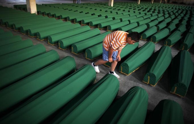 A Bosnian Muslim child searches for his relative's coffin which was prepared for a mass burial at the Memorial Center in Potocari, near Srebrenica July 9, 2012. The bodies of 520 recently identified victims of the Srebrenica massacre will be buried on July 11, the anniversary of the massacre when Bosnian Serb forces commanded by Ratko Mladic slaughtered 8,000 Muslim men and boys and buried them in mass graves, in Europe's worst massacre since World War Two. REUTERS/Dado Ruvic (BOSNIA - Tags: POLITICS CONFLICT ANNIVERSARY) Published: Čec. 9, 2012, 6:23 odp.