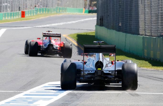 Ferrari Formula One driver Kimi Raikkonen of Finland (front) and McLaren driver Jenson Button of Britain leave the pit lane during the first practice session of the Austr