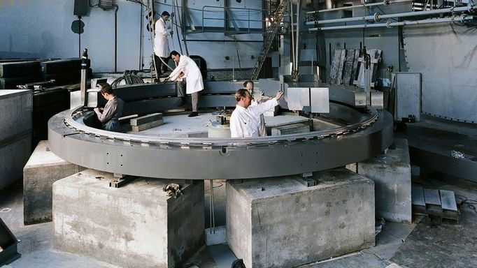 CERN, 1960: Vědci pracují na 5m magnetickém úložném prstenci pro druhý experiment s pozitrony a anomálním magnetickým momentem mionů. Kolorovaná fotografie.