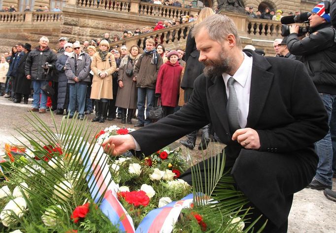 Rektor Univerzity Karlovy Václav Hampl upravuje stuhu na smutečním věnci.