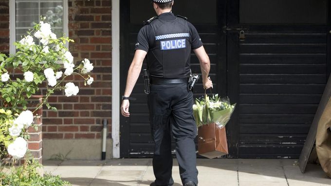 Policista nese květiny k domu zavražděných.