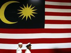 Američtí námořníci z letadlové lodi Kitty Hawk procházejí kolem obří státní vlajky Malajsie. Americké válečné plavidlo je v malajsijských vodách na pozvání tamní vlády právě u příležitosti oslav jubilea .