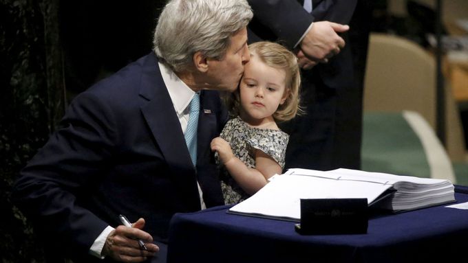 John Kerry podepisuje v New Yorku dohodu o klimatu s vnučkou v náručí.
