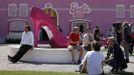 People relax outside a "Barbie Dreamhouse" of Mattel's Barbie dolls in Berlin, May 16, 2013. The life-sized house, covering about 1,400 square metres offers visitors to try on Barbie's clothes in her walk-in closet, tour her living room and her kitchen. REUTERS/Fabrizio Bensch (GERMANY - Tags: ENTERTAINMENT SOCIETY) Published: Kvě. 16, 2013, 10:59 dop.