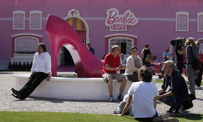 People relax outside a "Barbie Dreamhouse" of Mattel's Barbie dolls in Berlin, May 16, 2013. The life-sized house, covering about 1,400 square metres offers visitors to try on Barbie's clothes in her walk-in closet, tour her living room and her kitchen. REUTERS/Fabrizio Bensch (GERMANY - Tags: ENTERTAINMENT SOCIETY) Published: Kvě. 16, 2013, 10:59 dop.