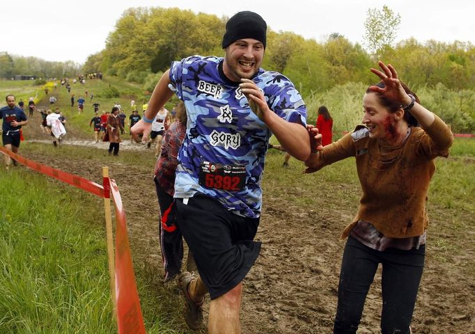 A zombie chases a runner (L) on the "Run for Your Lives" 5K obstacle course race in Amesbury, Massachusetts May 5, 2012. Runners face man-made and natural obstacles on the course, while being chased by zombies, who try to take "health" flags off the runners belts. REUTERS/Brian Snyder (UNITED STATES - Tags: SPORT SOCIETY) Published: Kvě. 5, 2012, 8:08 odp.