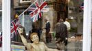 An ornament of a man carrying the Olympic torch stands in a shop window during Olympian celebrations in Much Wenlock, central England, July 14, 2012. Much Wenlock is revelling in the Olympics as a long-forgotten story about how this remote community inspired the modern Games receives global recognition. Although Athens is usually cited as the birthplace of the modern Games, that honour lies with the picture perfect 700-year-old English town. REUTERS/Darren Staples (BRITAIN - Tags: SPORT OLYMPICS SOCIETY TRAVEL) Published: Čec. 14, 2012, 4:36 odp.