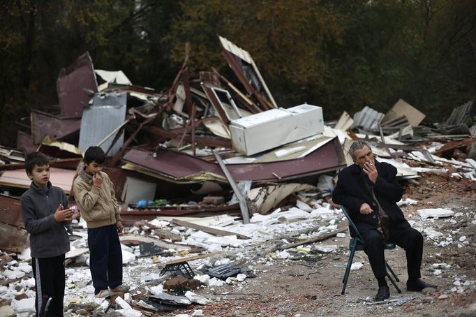 David Valdes Armendia and his brother Christian stand next to their great-uncle Mateo Echevarria after a bulldozer demolished the former school, where their grandparents lived at, in the Spanish gypsy settlement of Puerta de Hierro, in the outskirts of Madrid November 20, 2012. Fifty-four families have been living in Puerta de Hierro, on the banks of the Manzanares river for over 50 years. Since the summer of 2010, the community has been subject to evictions on the grounds that the dwellings are illegal. Families, whose homes have been demolished, move in with relatives whose houses still remain while the debris keeps piling up around them as more demolitions take place. REUTERS/Susana Vera (SPAIN - Tags: CIVIL UNREST BUSINESS CONSTRUCTION) Published: Lis. 20, 2012, 5:17 odp.