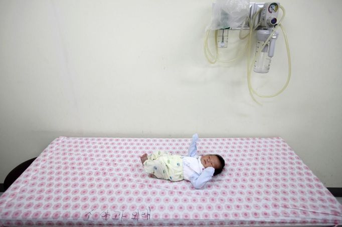 A baby abandoned in a "baby box" at Joosarang church waits for a medical examination at a children's hospital in Seoul September 19, 2012. Pastor Lee Jong-rak of the church, who runs a "baby box" where mothers can leave unwanted infants, has seen a sharp increase in the number of newborns being left there because, the pastor says, of a new law aimed protecting the rights of children. South Korea is trying to shed a reputation of being a source of babies for adoption by people abroad. It is encouraging domestic adoption and tightening up the process of a child's transfer from birth mother to adoptive parents. Picture taken September 19, 2012. REUTERS/Kim Hong-Ji (SOUTH KOREA - Tags: SOCIETY) Published: Říj. 7, 2012, 6:49 dop.