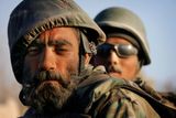 BOJOVNÍCI - Zaprášený voják Afghánské národní armády s květinou zastrčenou za uchem odpočívá na korbě hlídkujícího vozu poblíž Tálibánem ovládané pevnosti u města Panjwaii v provincii Kandahár. 13. listopad 2007.