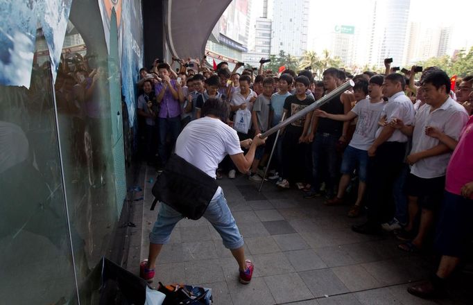 A protester hits a display window with a stick outside a Japanese shopping mall as fellow protesters applaud during an anti-Japan protest in Shenzhen, September 16, 2012. Chinese protesters took to city streets for a second day on Sunday to denounce Japan in a row over disputed islands, prompting the Japanese prime minister to call on Beijing to ensure protection of his country's people and property. REUTERS/Keita Van (CHINA - Tags: POLITICS CIVIL UNREST) CHINA OUT. NO COMMERCIAL OR EDITORIAL SALES IN CHINA