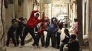 Gaza runner Bahaa al-Farra stretches during a training session as children mimic him while posing for the camera in Shati refugee camp in Gaza City