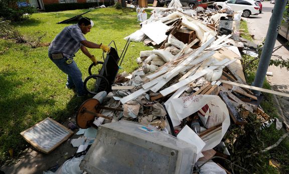 Majitelé zatopených domů v Houstonu vynášejí zničené vybavení.