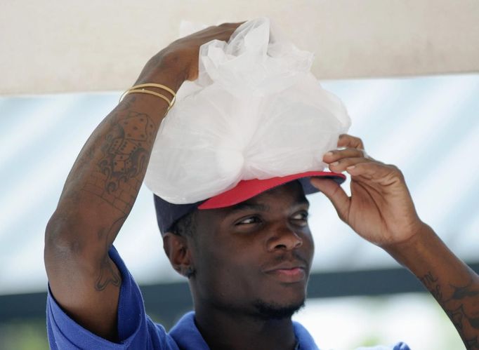 Turner Field vendor Demetrius Smith puts a bag of ice on his head as he tries to stay cool while working at the MLB National League baseball game between the Atlanta Braves and Washington Nationals in Atlanta, Georgia June 30, 2012. A record breaking heatwave has covered most of the country, with temperatures expected to reach 105 degrees Fahrenheit (41 degrees Celsius) in Atlanta. REUTERS/Tami Chappell (UNITED STATES - Tags: SOCIETY SPORT BASEBALL ENVIRONMENT) Published: Čer. 30, 2012, 10:59 odp.