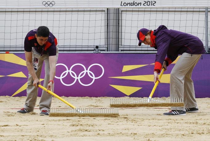 Simon Drew and Lenore Gerschwitz rake a practice beach volley ball court ahead of teams arriving for the London 2012 Olympic Games in London July 16, 2012. The London 2012 Olympic Games start in 11 days time. REUTERS/Luke MacGregor (BRITAIN - Tags: SPORT OLYMPICS VOLLEYBALL) Published: Čec. 16, 2012, 4:30 odp.