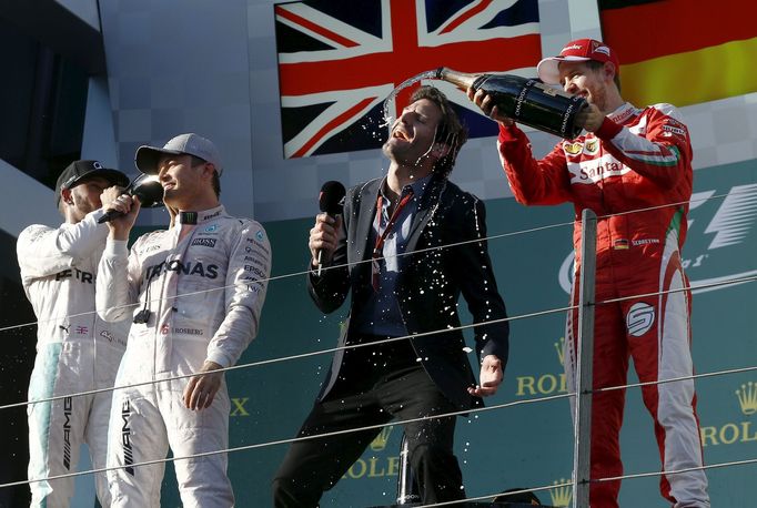 Australian former F1 driver Mark Webber (2nd R) has champagne poured on him by tSebastian Vettel (R) as he interviews Nico Rosberg (2nd L) in Melbourne.