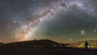 Petr Horálek u observatoře Paranal. Mléčná dráha (Milky Way) se táhne nad osvětlenou kupolí astronomického hotelu - nazývá se La Residencia - která byla speciálně navržena tak, aby nevytvářela žádné světelné znečištění, které by mohlo rušit provoz dalekohledů. Rozmáznutá telená skvrna vlevo dole je kometa, jež se stala pátou nejblíže Zemi prolétající kometou v zaznamenané historii.