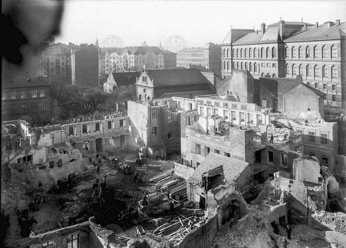 "Bourání Hampejzu". Pohled na bourání domů v Josefově Vlevo část budovy Všeobecné židovské nemocnice (dům čp. 248 v Josefově) a část Starého židovského hřbitova. Rok 1910