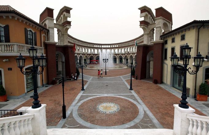 Two women walk through a building that resembles a Roman Coliseum at the Florentia Village in the district of Wuqing, located on the outskirts of the city of Tianjin June 13, 2012. The shopping center, which covers an area of some 200,000 square meters, was constructed on a former corn field at an estimated cost of US$220 million and copies old Italian-style architecture with Florentine arcades, a grand canal, bridges, and a Coliseum-like building. REUTERS/David Gray (CHINA - Tags: SOCIETY BUSINESS) Published: Čer. 13, 2012, 5:21 odp.