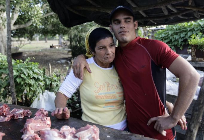 Luis Salgado (R), nicknamed Chucho, hugs his mother Niurka during a pig slaughter at their home in the village of Sagua La Grande in central Cuba, March 10, 2013. Chucho was granted a U.S. visa based on his father's status as legal resident in Texas, and he was reunited in Miami with his father, Jesus Salgado, who had escaped Cuba on a frail boat ten years earlier. The Salgados are among many Cubans taking advantage of Cuba's new travel policy in place since last January, which allows citizens to leave the country with just a passport and no need for much-hated exit visas required since 1961. Picture taken March 10, 2013. REUTERS/Desmond Boylan (CUBA - Tags: POLITICS SOCIETY) Published: Dub. 11, 2013, 1:07 odp.